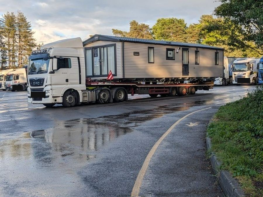 Static caravan on a low-loader in the yard