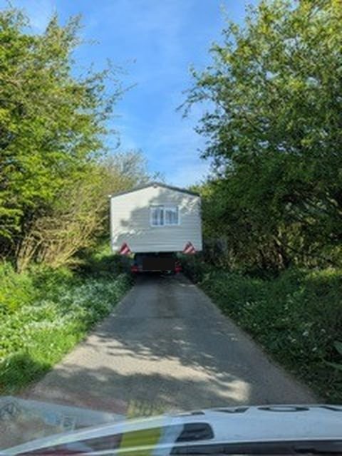 Static caravan being reversed down a narrow lane